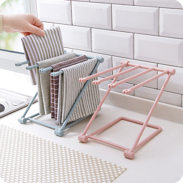 Foldable dishcloth shelf holding wet kitchen towels and sponge by a sink