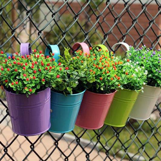 Black wall basket hanger holding a pot with green plants on outdoor wall